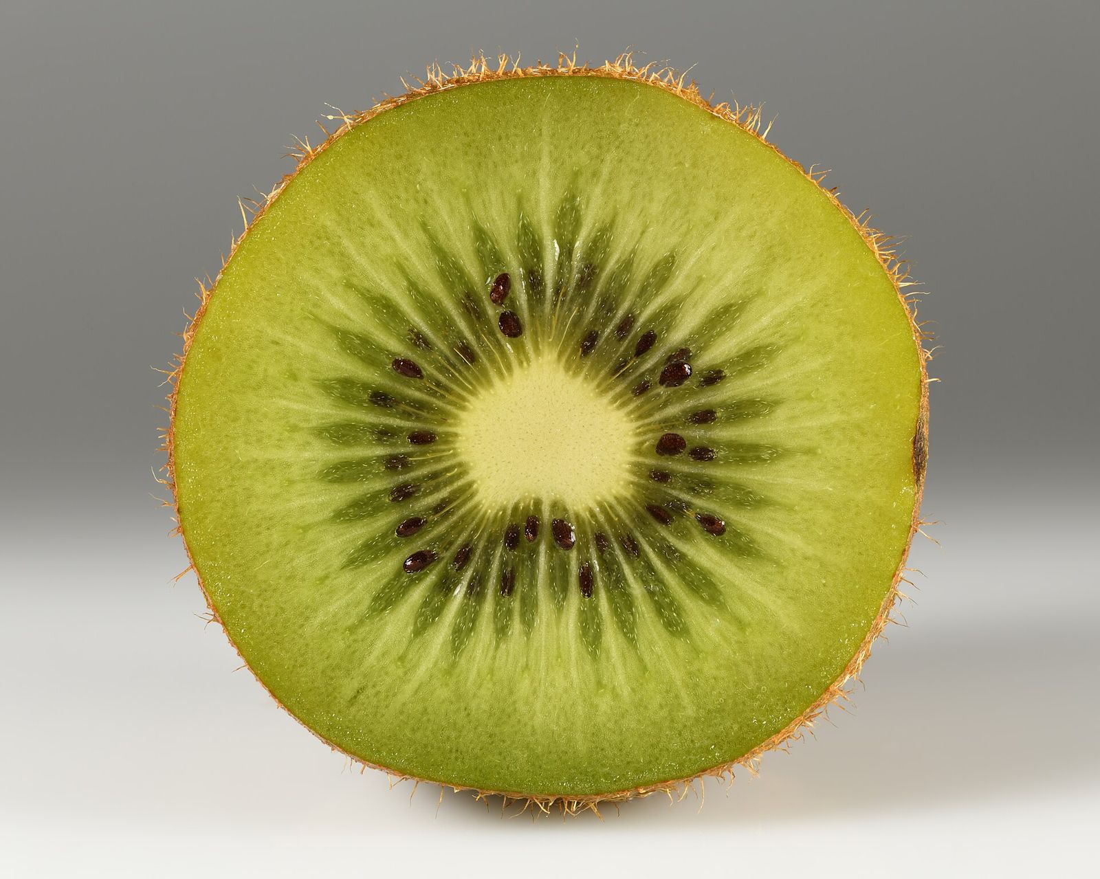 A kiwifruit cut in half showing green flesh and black seeds